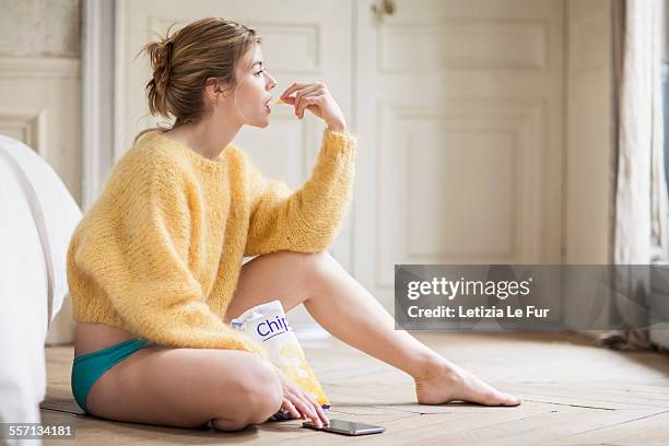 woman using phone and eating chips - potato chip stock pictures, royalty-free photos & images