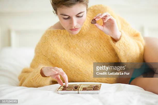 woman eating chocolate on bed - woman chocolate stock pictures, royalty-free photos & images