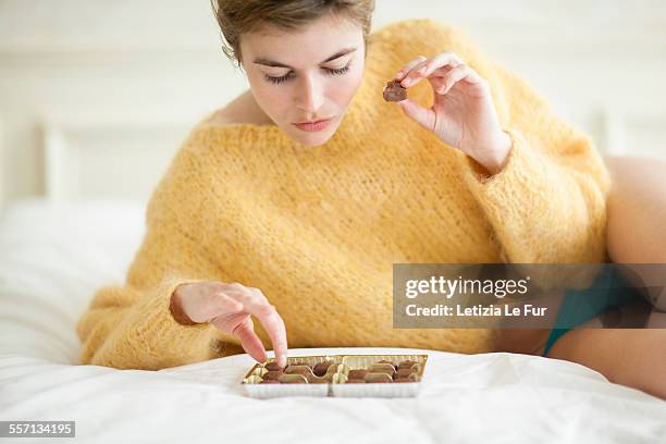 woman eating chocolate on bed - mulher comendo chocolate imagens e fotografias de stock