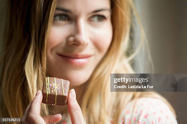 woman eating a chocolate - chocolate foto e immagini stock