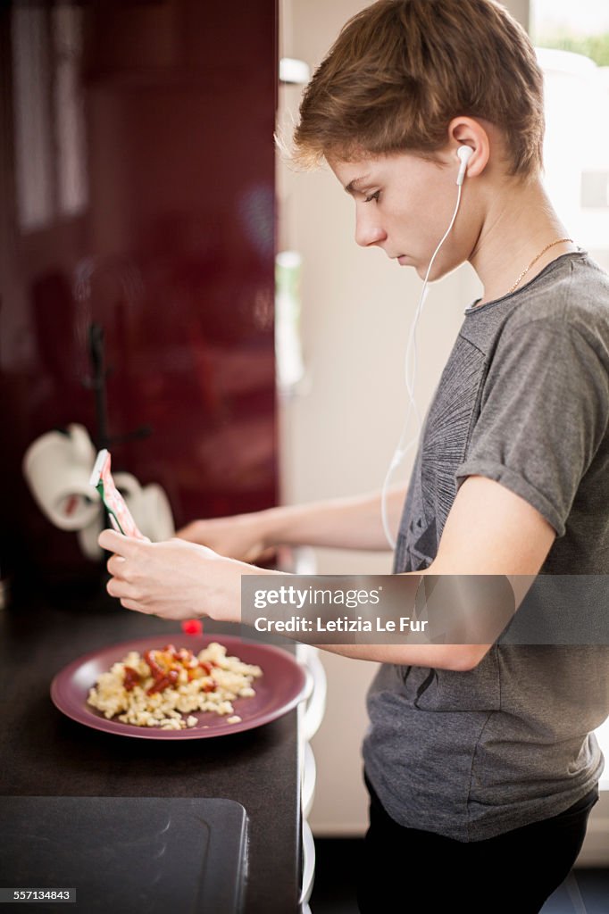 Teenage boy listening to music with breakfast