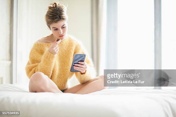 woman using phone and eating chocolate on bed - woman chocolate stock pictures, royalty-free photos & images