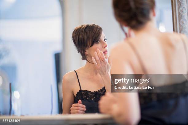 woman applying anti-aging cream on her face - anti age stock-fotos und bilder