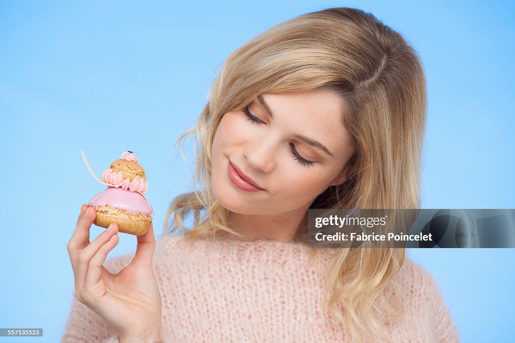 Close-up of a beautiful woman holding a french strawberry religieuse