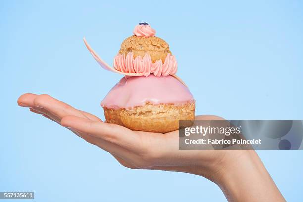 close-up of a womans hand holding a french strawberry religieuse - relámpago de crema fotografías e imágenes de stock