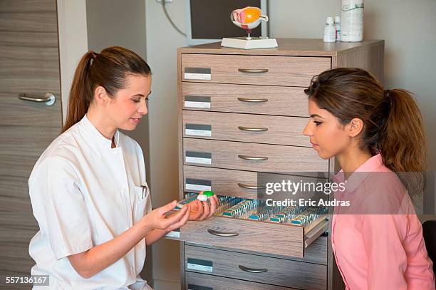 female optician showing contact lens to woman - lenti a contatto foto e immagini stock