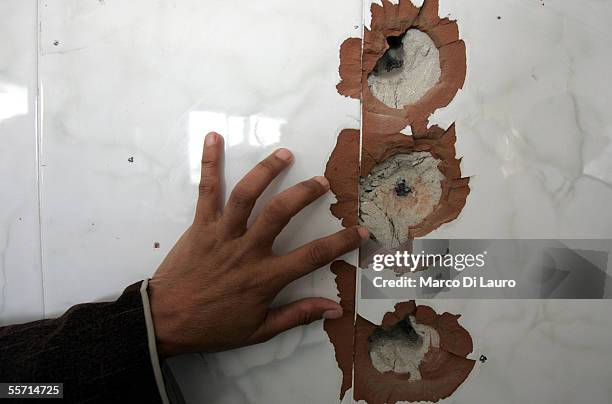 Adla Abu Areef, 33-years-old, the wife of the brother of Ali Abu Areef, 45-years-old, points to a bullet scarred wall in their house on September 18,...