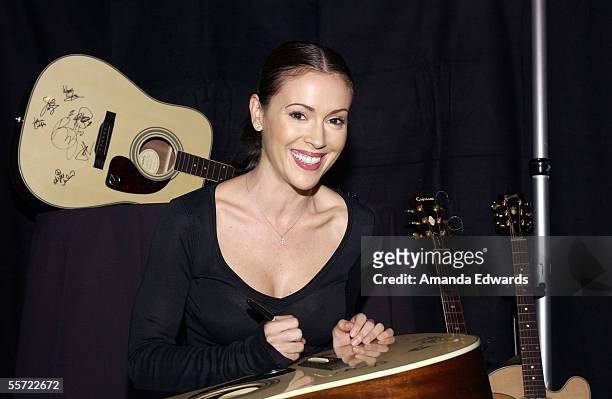 Actress Alyssa Milano signs a Gibson guitar at the "ReAct Now: Music & Relief" benefit concert at Paramount Studios on September 9, 2005 in...