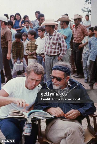 American actor Steve McQueen points to the script as he discusses a scene with director Sam Peckinpah on the set of Peckinpah's 'The Getaway,' 1972....