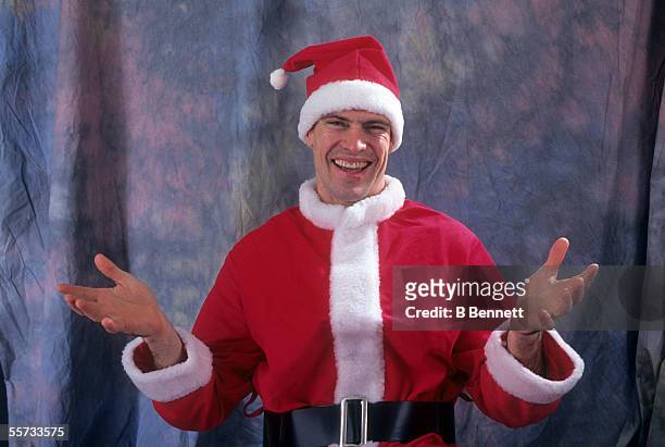 Canadian professional hockey player Mark Messier makes a non-threatening gesture as he wears a Santa Claus hat and jacket during a photo shoot,...