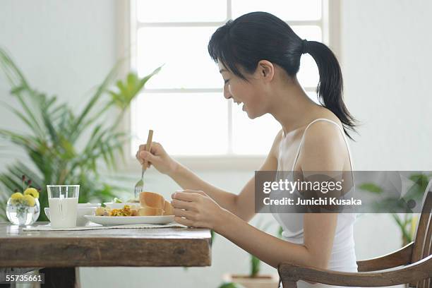 a young woman eating breakfast - キャミソール ストックフォトと画像