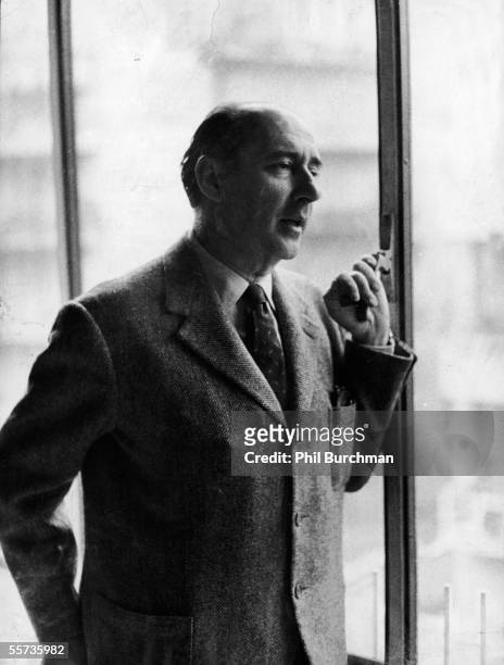 Portrait of Italian motion picture director Roberto Rossellini as he stands at a window in a tweed jacket and talks to someone out of frame, Rome,...