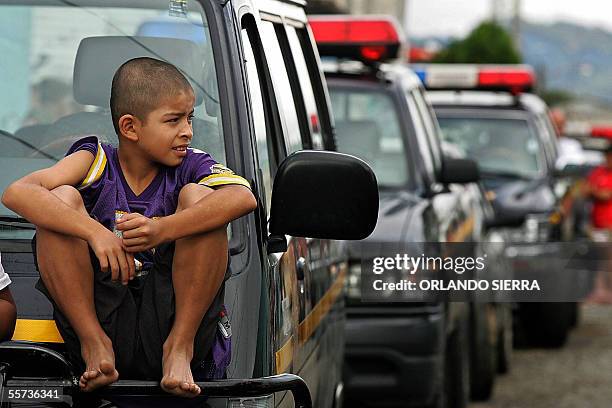 Un nino observa, sentado sobre un movil policial, el operativo de la Policia Nacional Civil y del Ejercito de Guatemala contra miembros de la Mara 18...