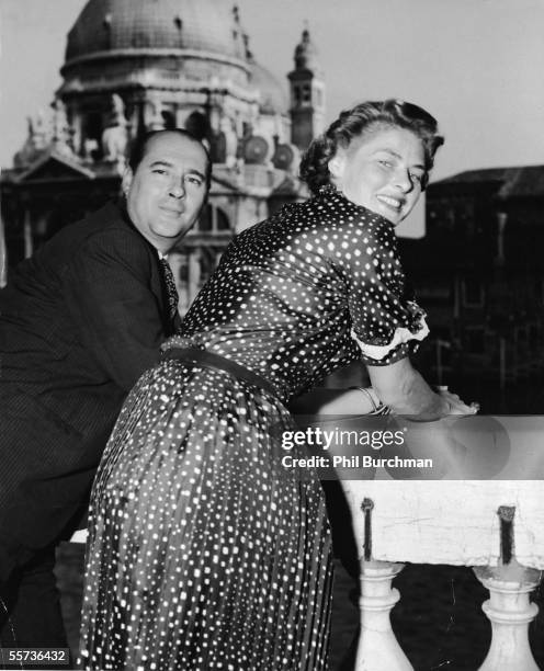 Italian motion picture director Roberto Rossellini and his second wife Swedish actress Ingrid Bergman lean on the railing of a balcony overlooking...