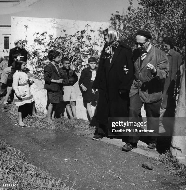 Swedish actress Ingrid Bergman and her second husband Italian motion picture director Roberto Rossellini walk arm-in-arm past some local children on...