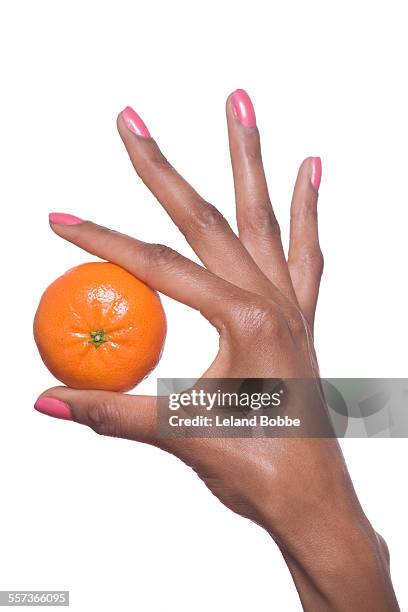 woman's hand holding a tangerine - nagellack stock-fotos und bilder
