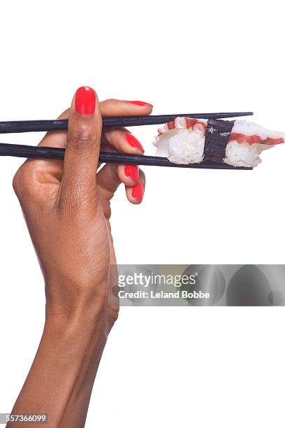 woman's hand holding sushi with chopsticks - chopsticks stock pictures, royalty-free photos & images