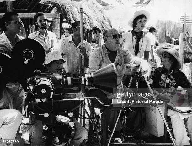 Italian motion picture director Roberto Rossellini sits and listens to his first wife Italian costume designer Marcella de Marchis as his daughter,...