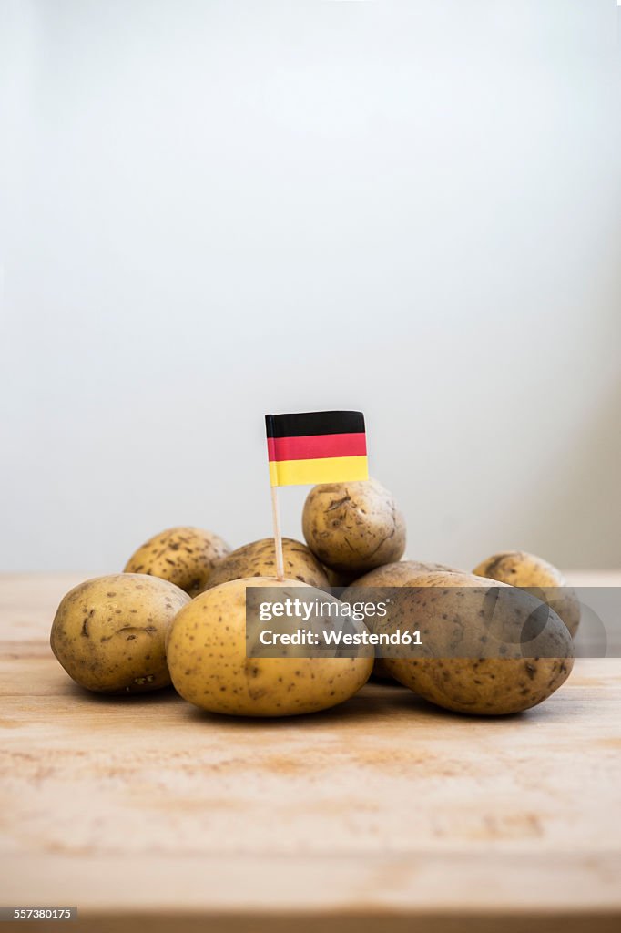 Row potatoes and small german little flag on wood
