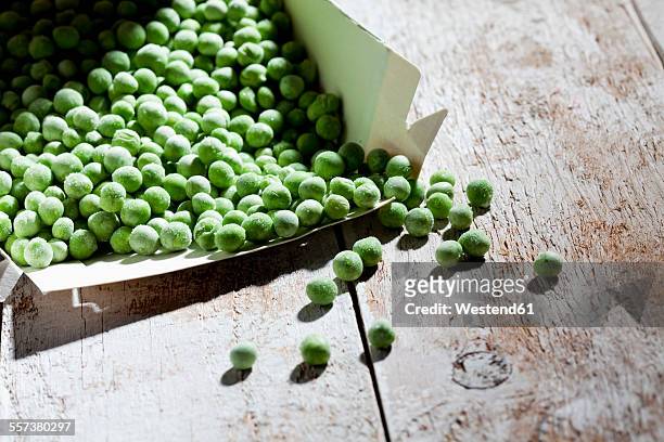 opened package of deep frozen peas on wood - gefrierkost stock-fotos und bilder