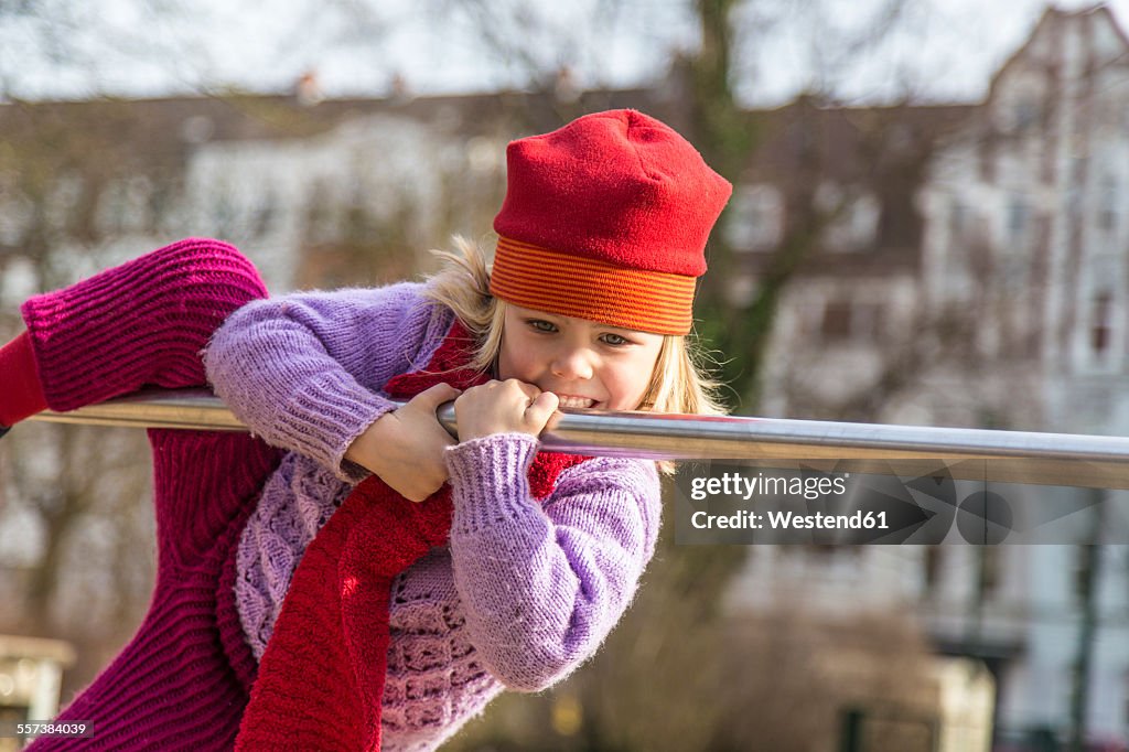 Germany, Kiel, Little girl with red cap playing on bar