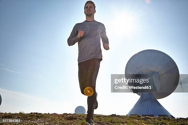 germany, raisting, young man jogging at ground station - raisting stock-fotos und bilder