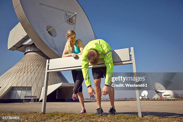 germany, raisting, young jogger couple having a rest at ground station - raisting stock-fotos und bilder