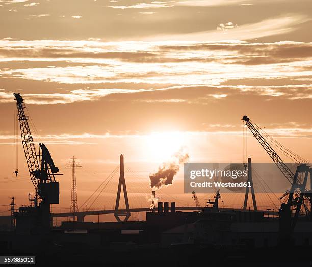 germany, hamburg, silhouettes of harbour cranes at sunset, koehlbrand bridge in the background - köhlbrandbrücke stock pictures, royalty-free photos & images