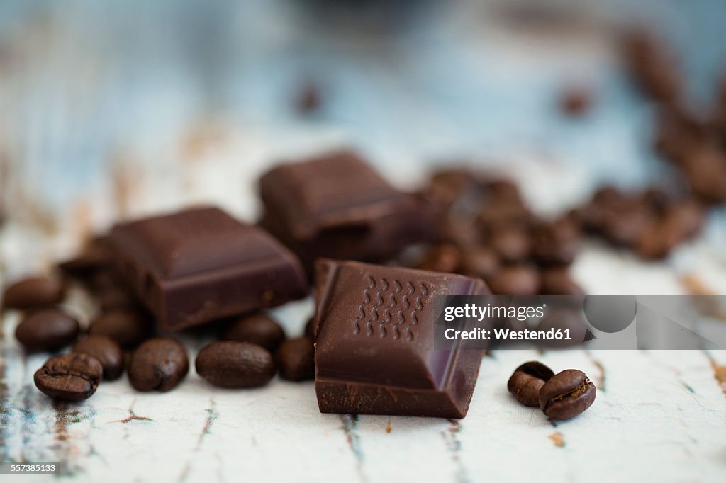 Roasted coffee beans and pieces of dark chocolate on wood