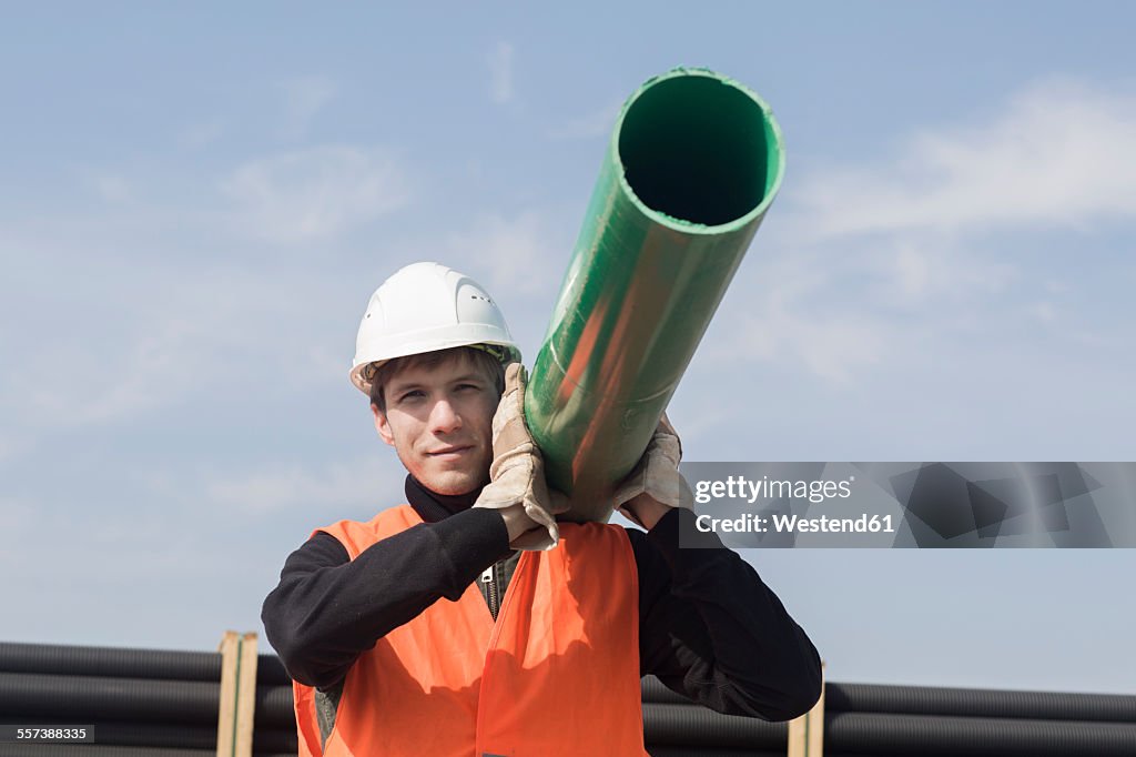 Construction worker carrying pipe on his shoulder