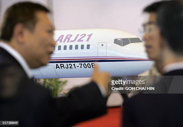 Visitors discuss various business deals beside the display of a model of the ARJ21 aircraft at the China Aviation Industry Corporation I booth during...