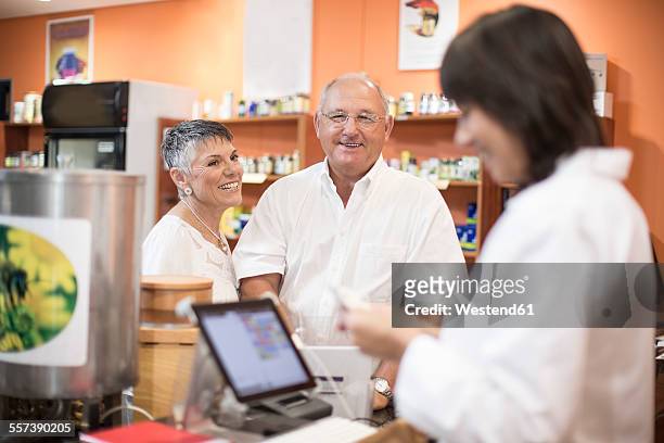 senior couple paying in health shop - mujeres de mediana edad fotografías e imágenes de stock