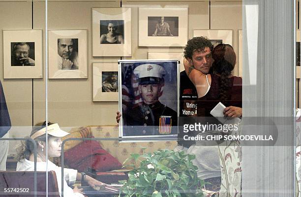 Washington, UNITED STATES: Carolos Arredondo holds a photograph of his son, US Marine Lance Cpl. Alexander Arredondo, while embracing a fellow...