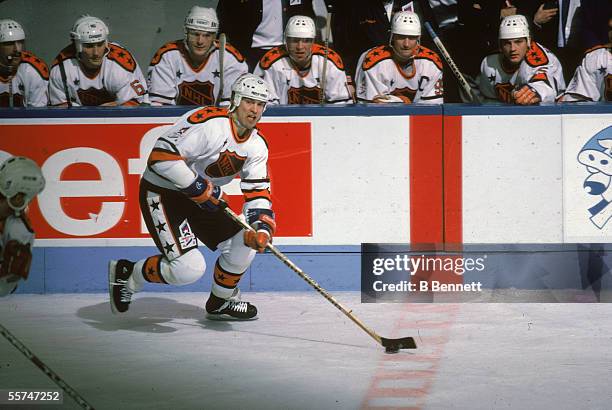 Canadian professional hockey player Mark Messier, center for the Edmonton Oilers, follows the puck and skates past his teammates sitting at the bench...