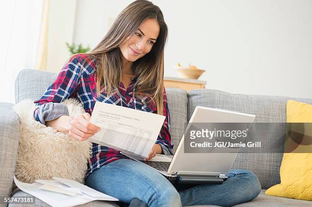 caucasian woman paying bills on laptop - femme facture photos et images de collection