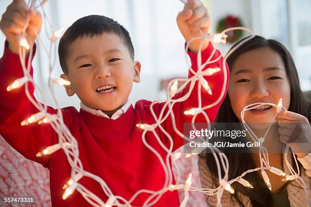 asian children playing with christmas string lights - hanging christmas lights stock pictures, royalty-free photos & images