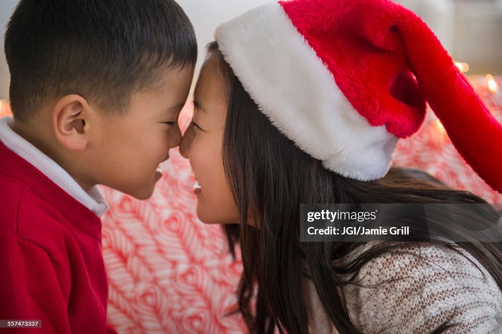 Asian brother and sister rubbing noses at Christmas