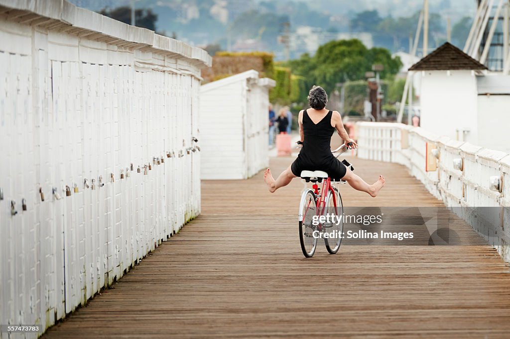 Older Caucasian woman riding bicycle on wooden dock