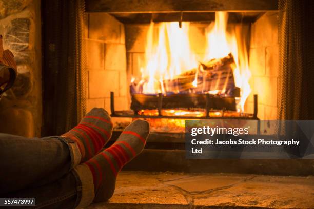 caucasian woman warming feet near fireplace - fogueira imagens e fotografias de stock