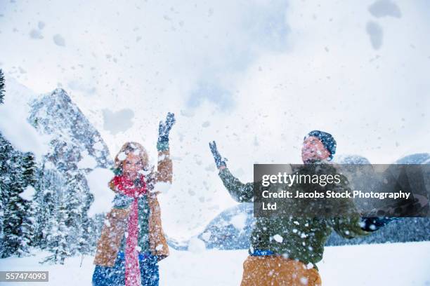caucasian couple playing in snow near mountains, lake louise, alberta, canada - man standing in the snow stock-fotos und bilder