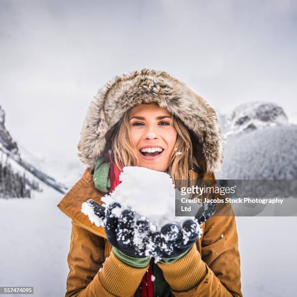 caucasian woman holding snow near mountains, lake louise, alberta, canada - parka cappotto invernale foto e immagini stock