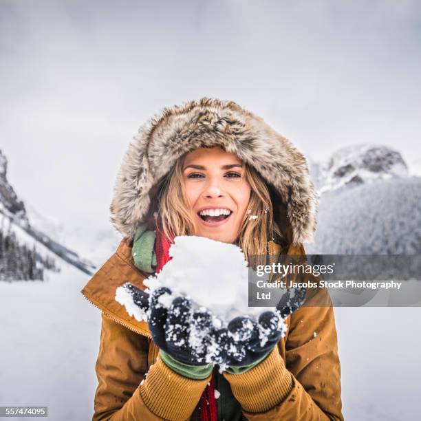 caucasian woman holding snow near mountains, lake louise, alberta, canada - parka stock pictures, royalty-free photos & images