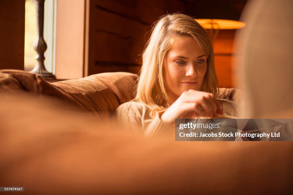 Caucasian woman reading book on sofa