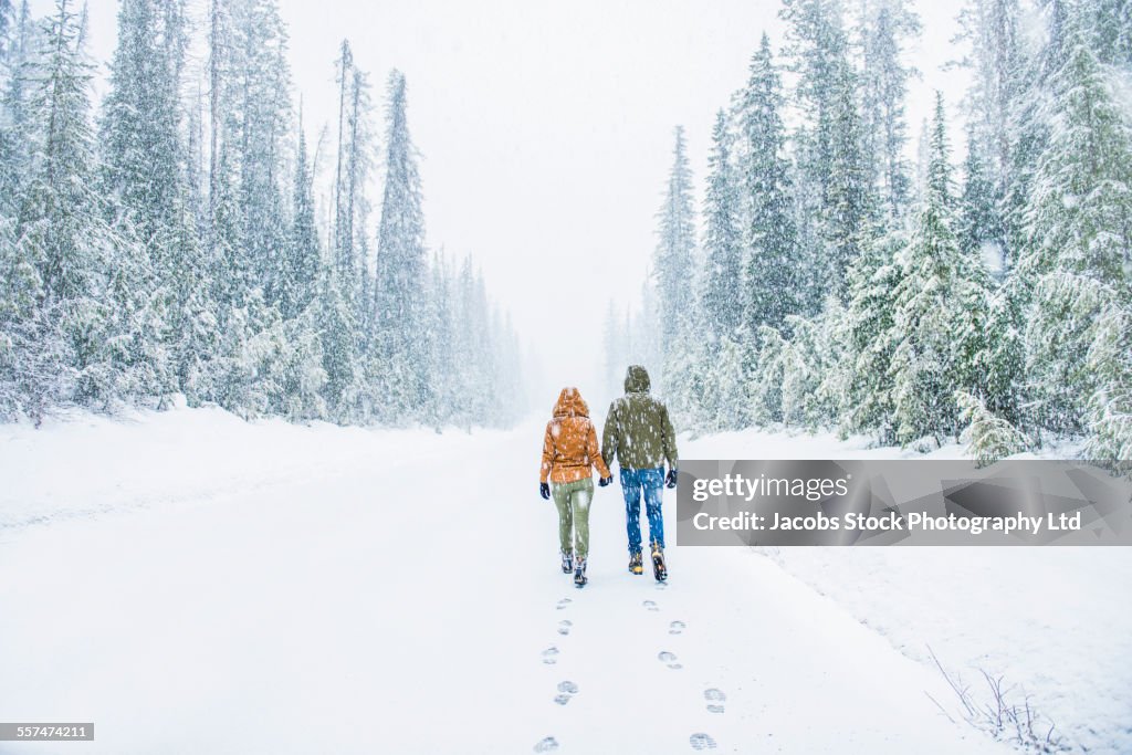 Caucasian couple walking on snowy forest road