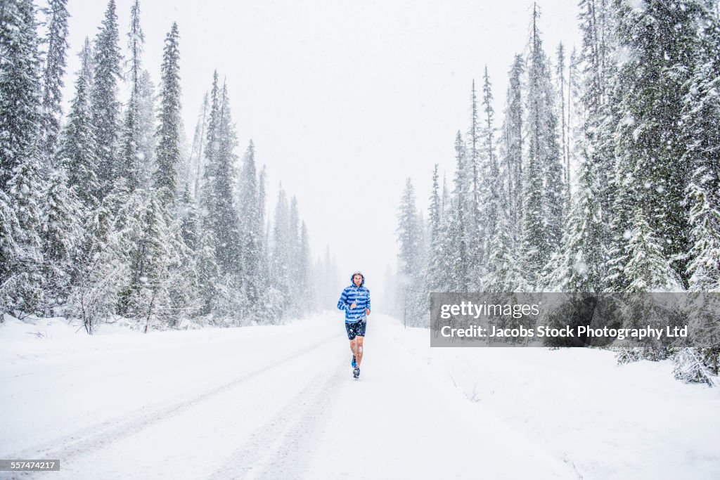 Caucasian man running on snowy forest road