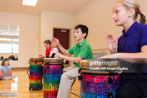 children playing bongo drums in music class - instrumentos de percusión fotografías e imágenes de stock