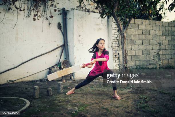 mixed race girl playing cricket near wall - cricketbat stockfoto's en -beelden