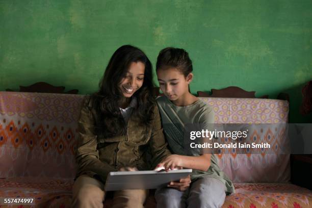 aunt and niece using digital tablet on sofa - indian aunt stock pictures, royalty-free photos & images