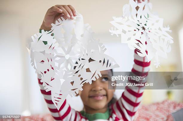mixed race girl holding paper snowflakes - craft stock pictures, royalty-free photos & images