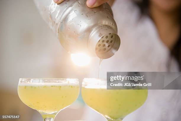 pacific islander woman pouring cocktails from shaker - cocktail making stock pictures, royalty-free photos & images